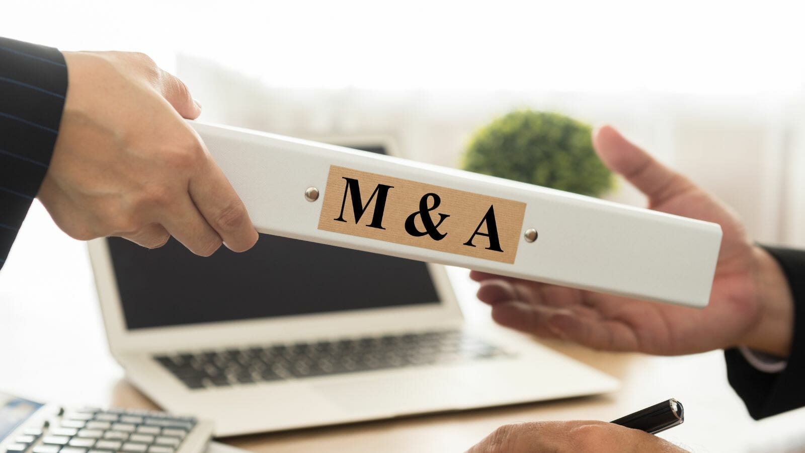 A person holding a white rectangular object with a sign on it M&A