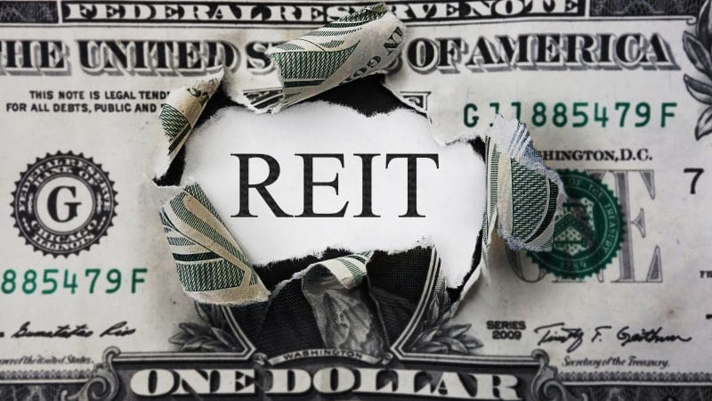 a dollar bill with the word REIT expliding through the center