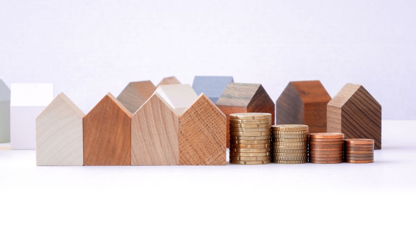 picture of wooden houses and money stacked up next to the houses