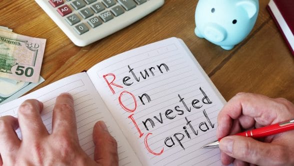A person writing return on invested capital in a notebook