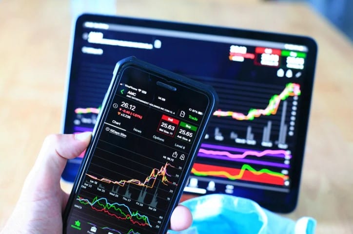 Person looking at stocks on both their phone and tablet