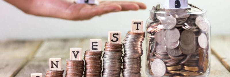 wooden blocks on coins spelling the words invest