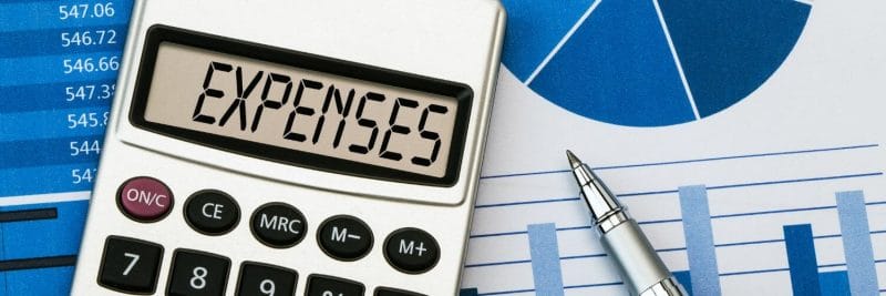 A close-up of a calculator and a pen
with the word expenses