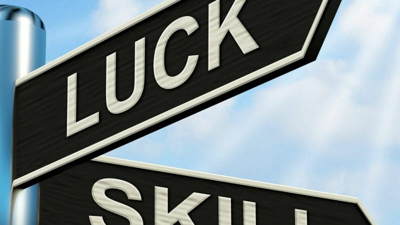 A close-up of a street sign with the words skill and luck

