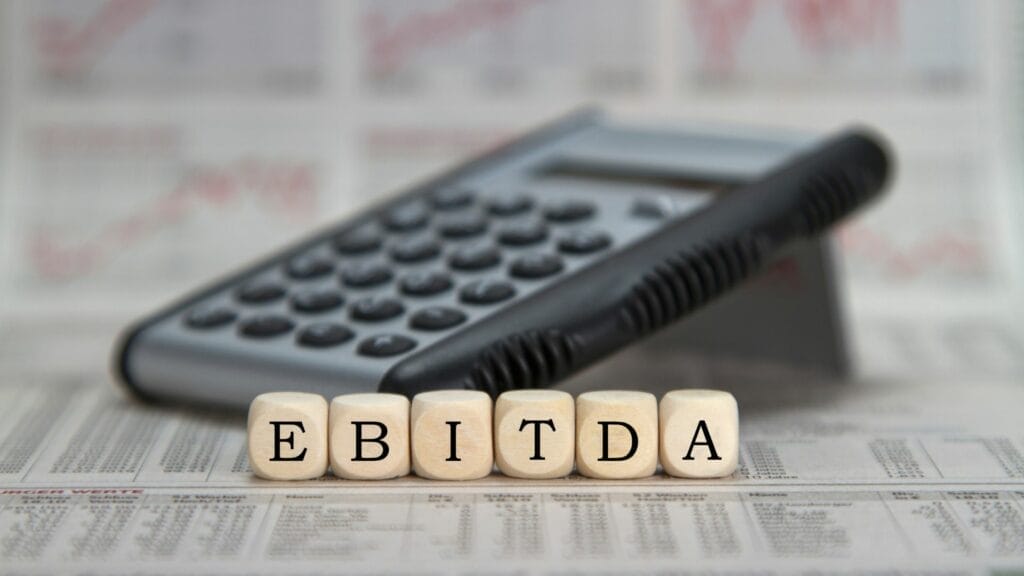 Calculator with blocks spelling EBITDA in front of it