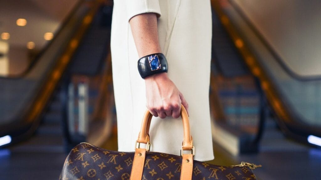A person holding a purse with a watch on