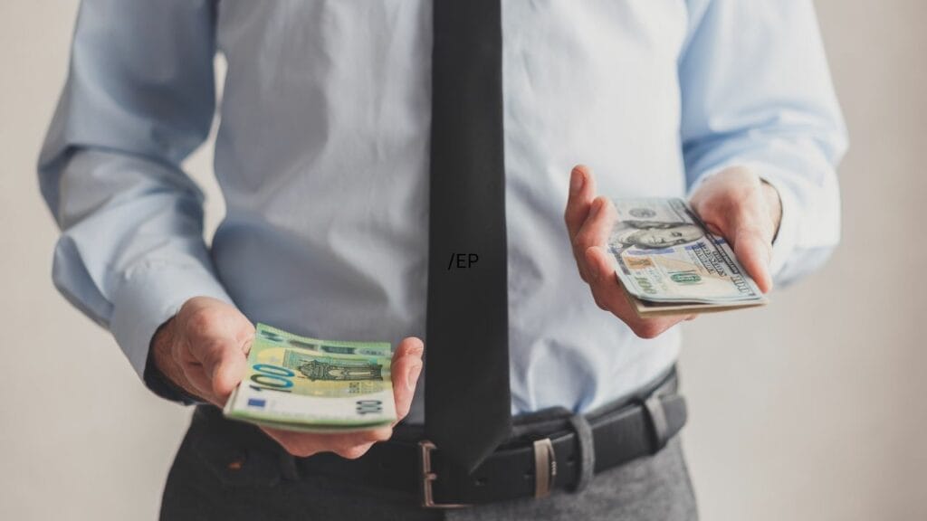 A person holding two different currencies and wearing a tie