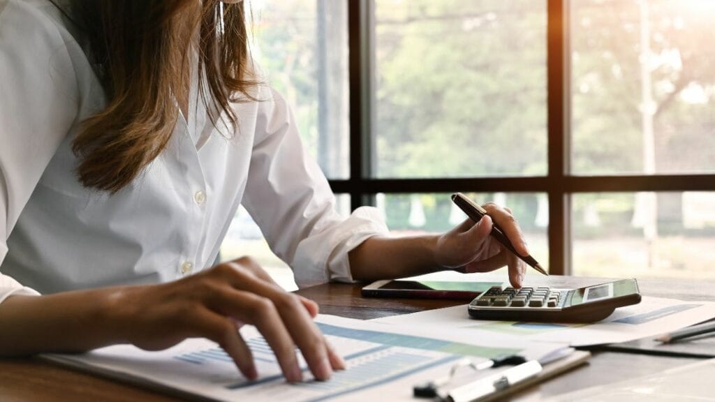 A person holding a pen using a calculator